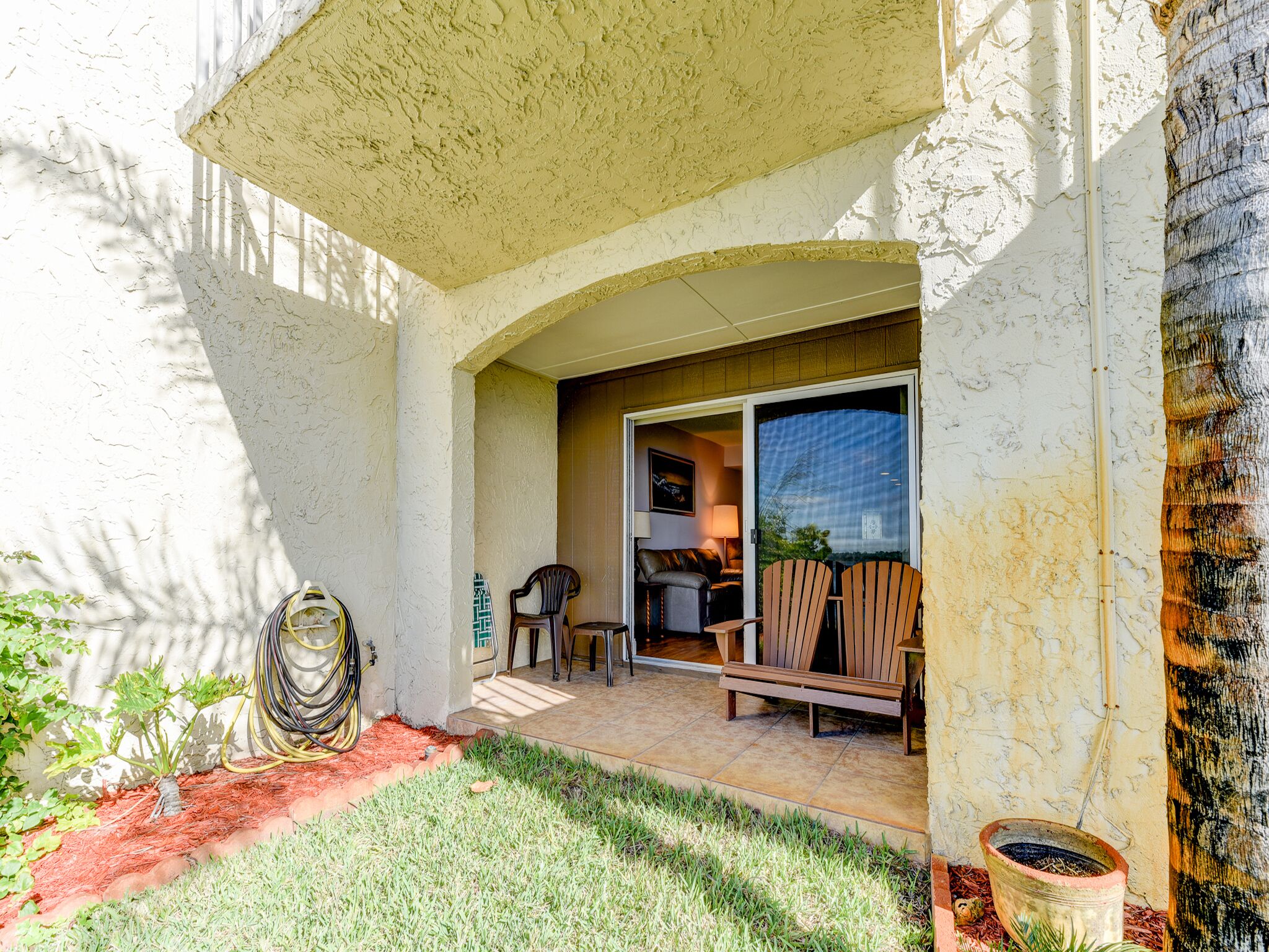 A covered patio area with a seating arrangement, a small garden, and a view of the outdoors.