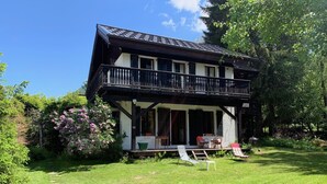 A two-story house with a balcony, surrounded by lush greenery and flowering plants. - Ideally located chalet with Mont Blanc view (Chamonix-Mont-Blanc)