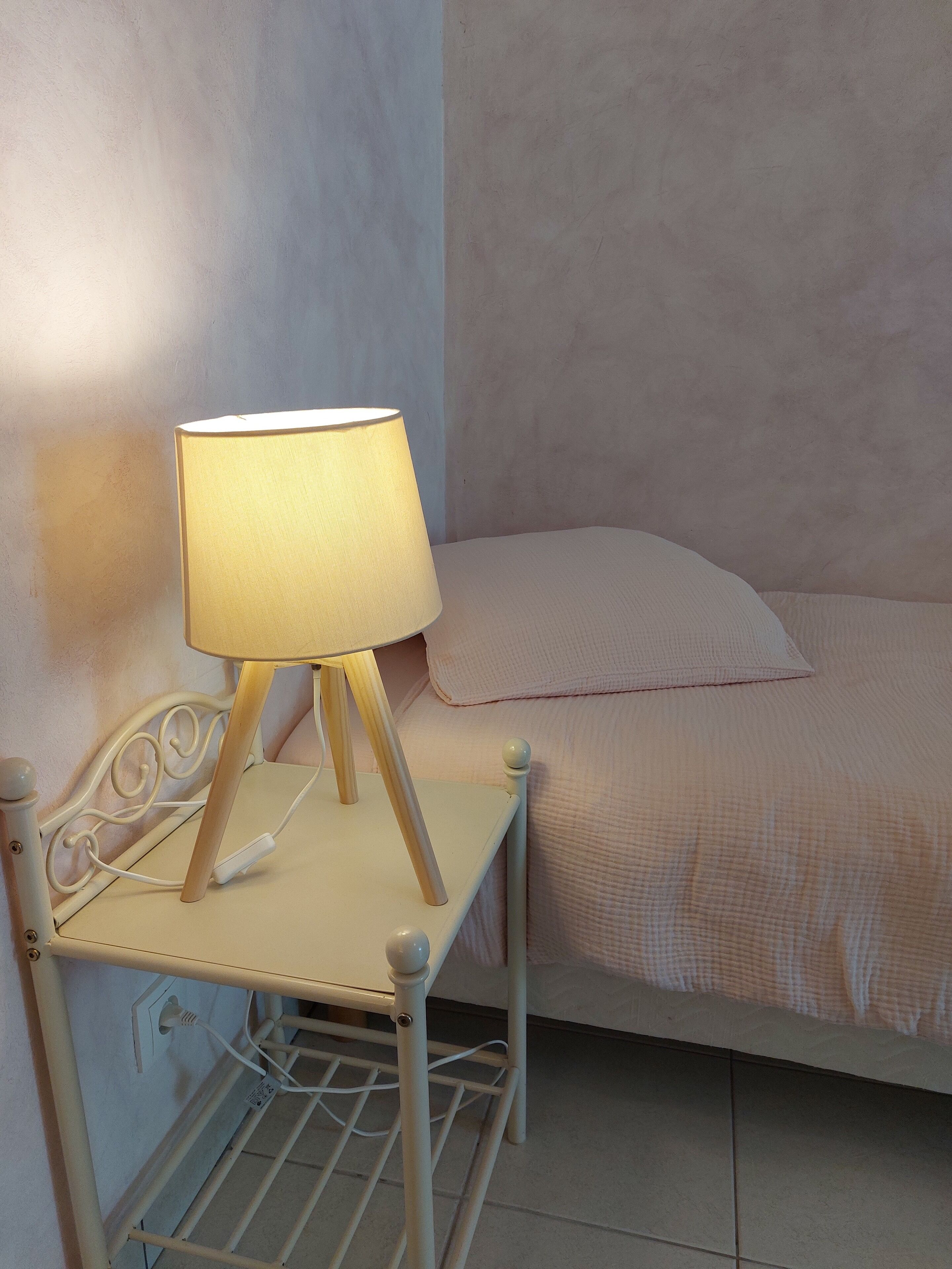A bed with a white headboard and a bedside table with a lamp.