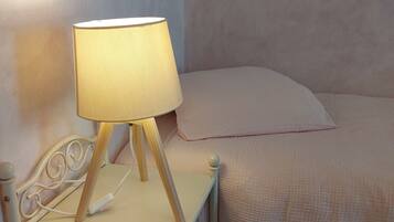 A bed with a white headboard and a bedside table with a lamp.