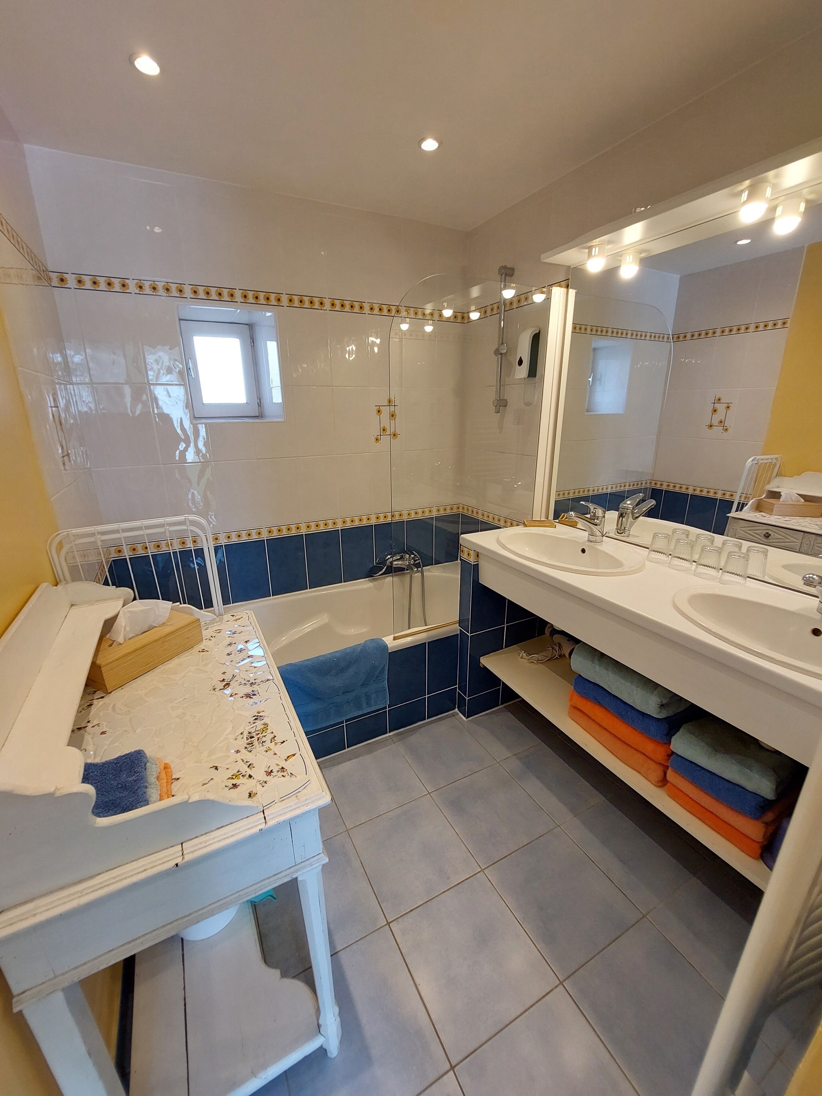 A bathroom with a bathtub, two sinks, a mirror, and a window.