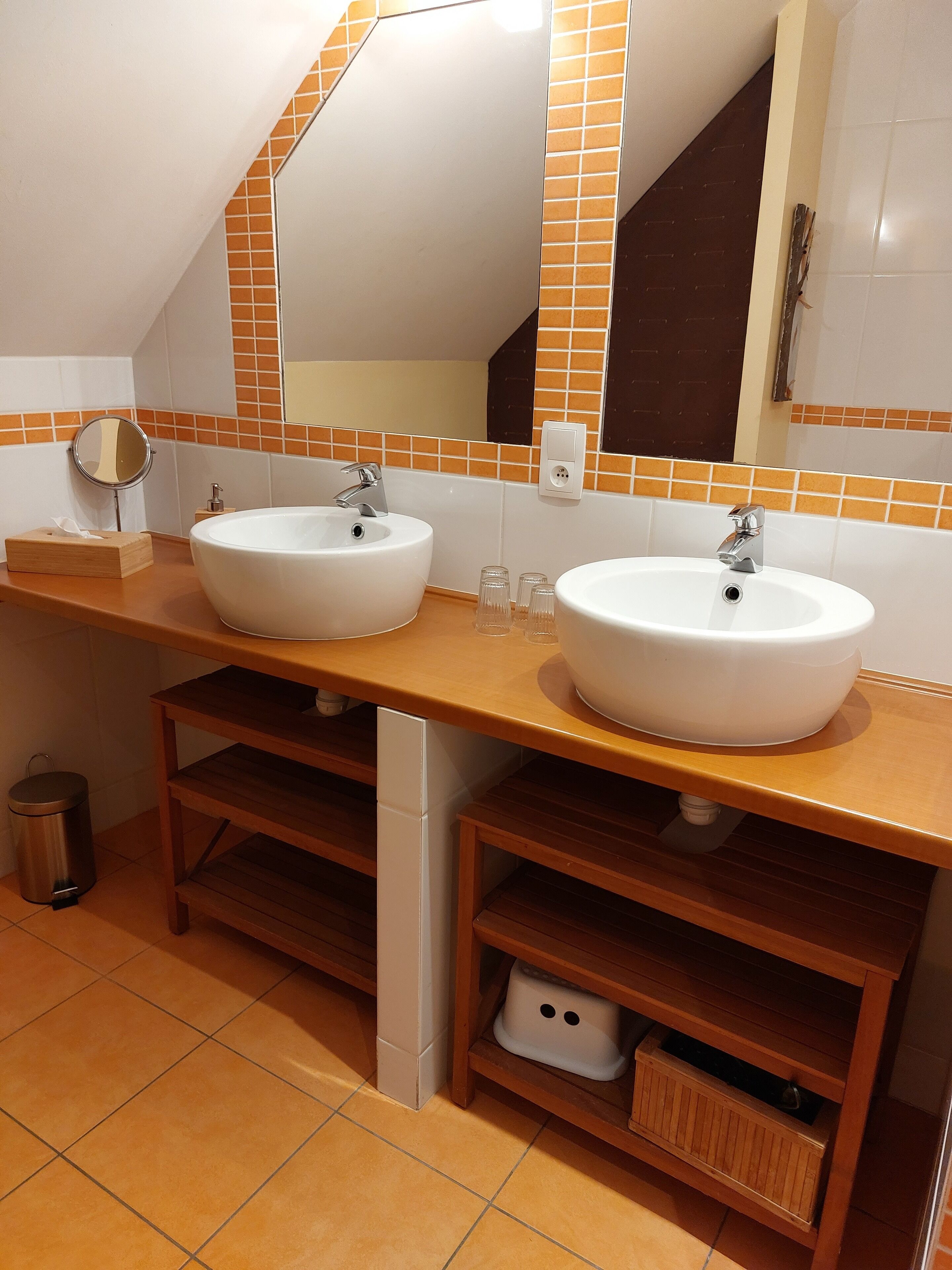 Een badkamer met twee wastafels, een spiegel en een zeepdispenser.