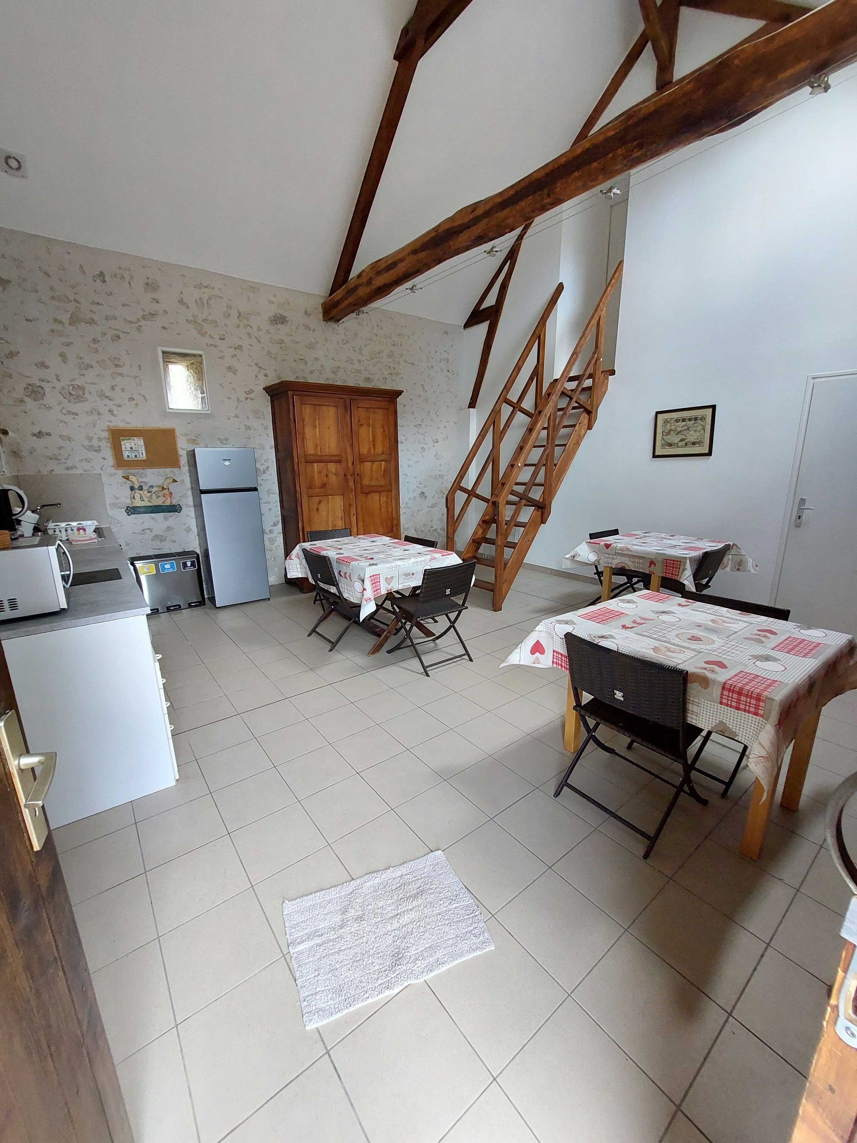 A kitchen with a dining area, wooden staircase, and a refrigerator.