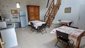 A kitchen with a dining area, wooden staircase, and a refrigerator.
