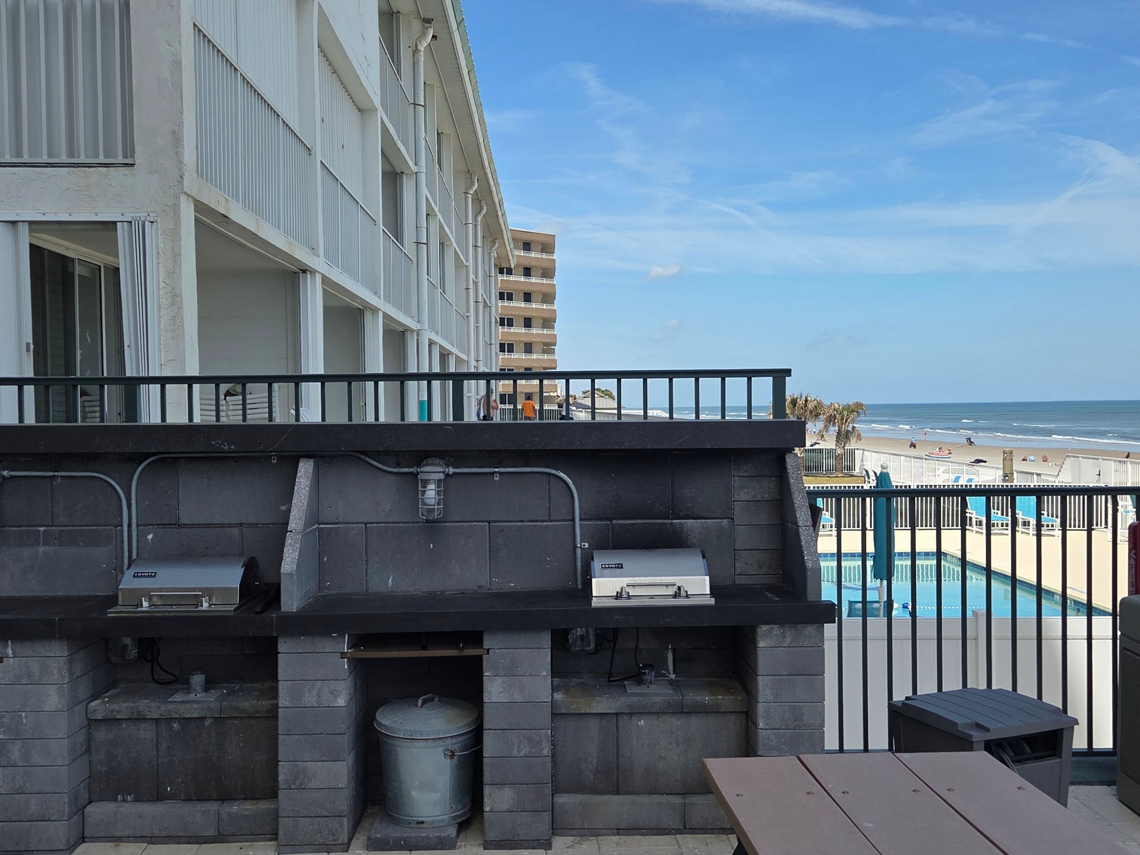 A balcony with a grill and a view of the beach.