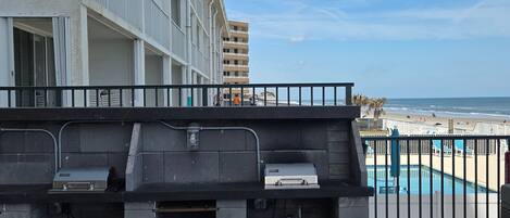 A balcony with a grill and a view of the beach.