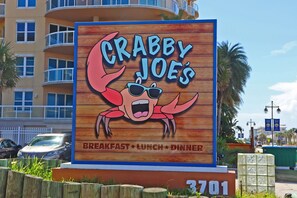 A sign for Crabby Joe's restaurant with a crab illustration, indicating it serves breakfast, lunch, and dinner.