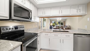 Una cocina moderna con armarios blancos, electrodomésticos de acero inoxidable y encimera de granito.
