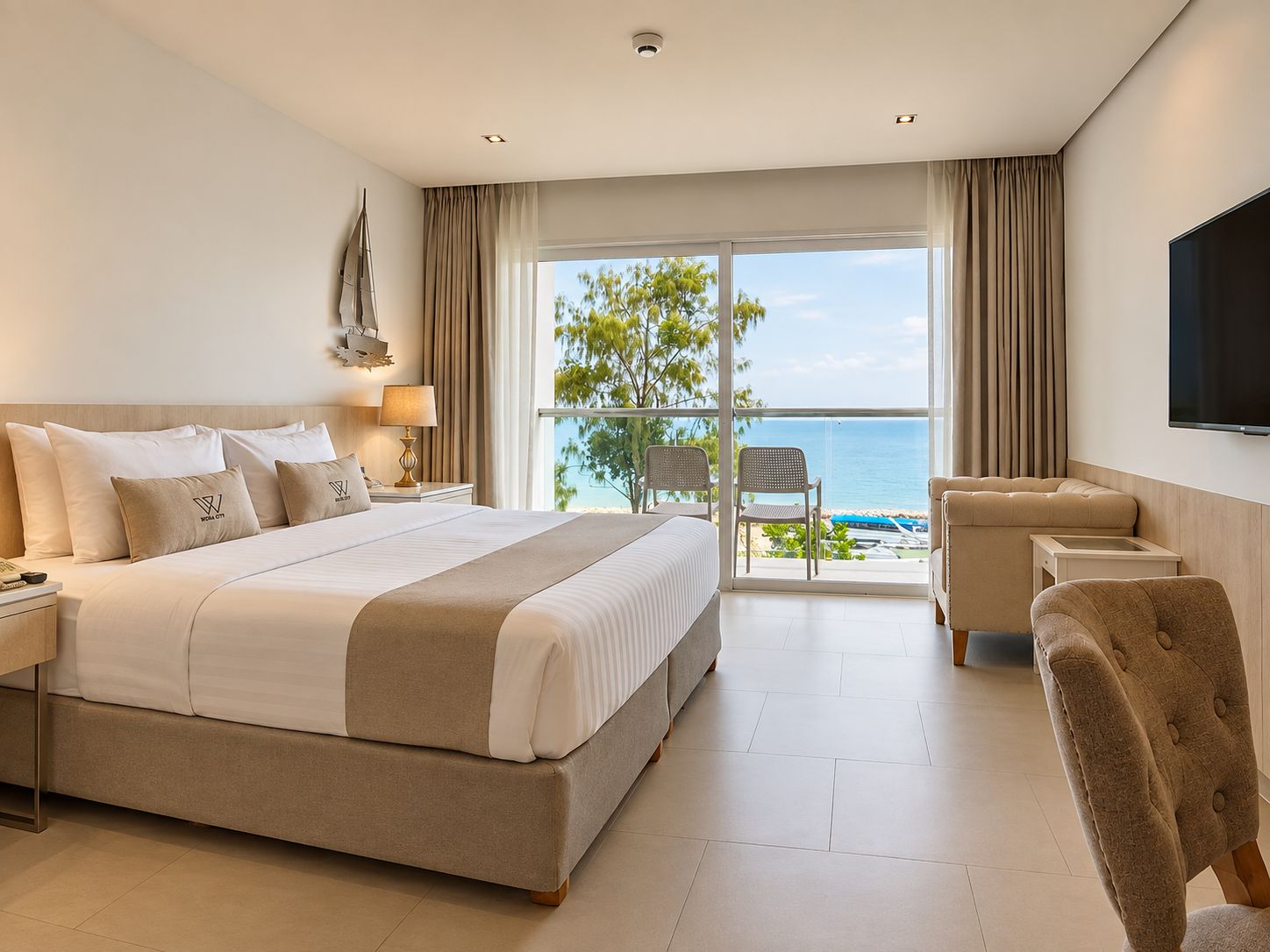 A hotel room with a large bed, a TV, a balcony with a view of the sea, and a chair.