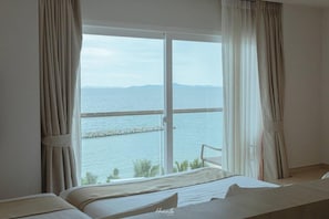 Enjoy a serene sea view from the comfort of your room, featuring a plush bed and a convenient bedside table.