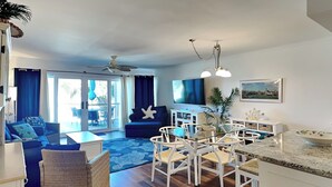 Un salon moderne comprenant un canapé, une table à manger avec des chaises, un coin cuisine avec un évier et un ventilateur de plafond.