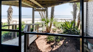 Vue sur la plage depuis un patio couvert doté d’une terrasse en bois et d’un mur en béton.