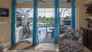 A spacious living area with a view of a pool and outdoor patio. - Seas the Day by Distinctive Beach Rentals (Flagler Beach)
