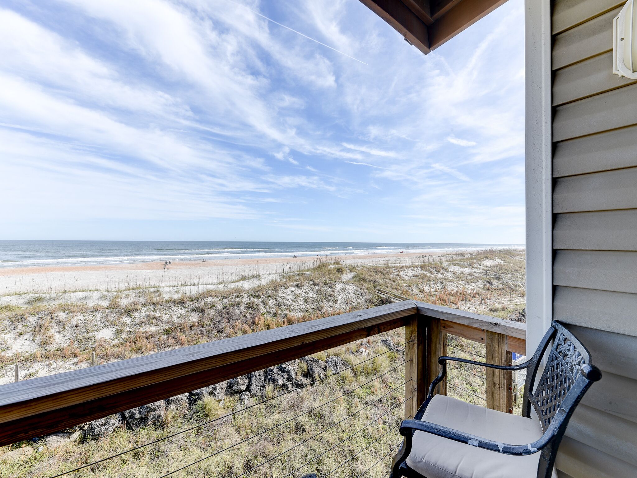 A balcony with a view of a beach and dunes.