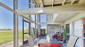 A sunlit patio with a table and chairs, large windows, and a view of a green field. - Ponte Vedra Deer Run 9770 by Distinctive Beach Rentals (Ponte Vedra Beach)