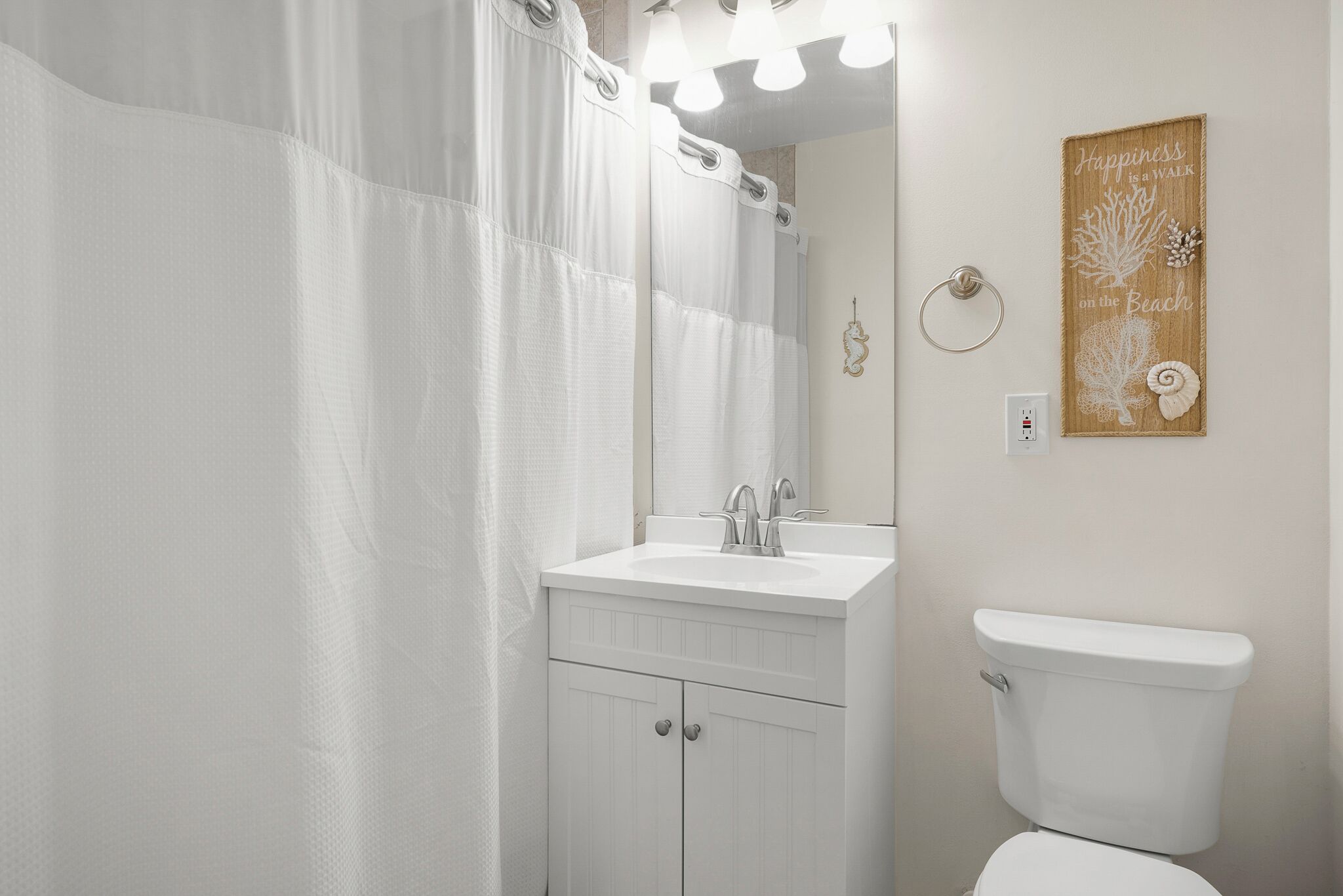 A bathroom with a white sink, a toilet, and a shower curtain.