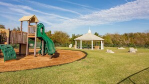 A playground with a slide, a climbing structure, and a gazebo. - Sun Kissed Cottage by Distinctive Beach Rentals (St. Augustine)