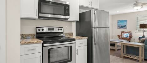 A kitchen with stainless steel appliances, white cabinets, granite countertops, and a dining area with a table and chairs.