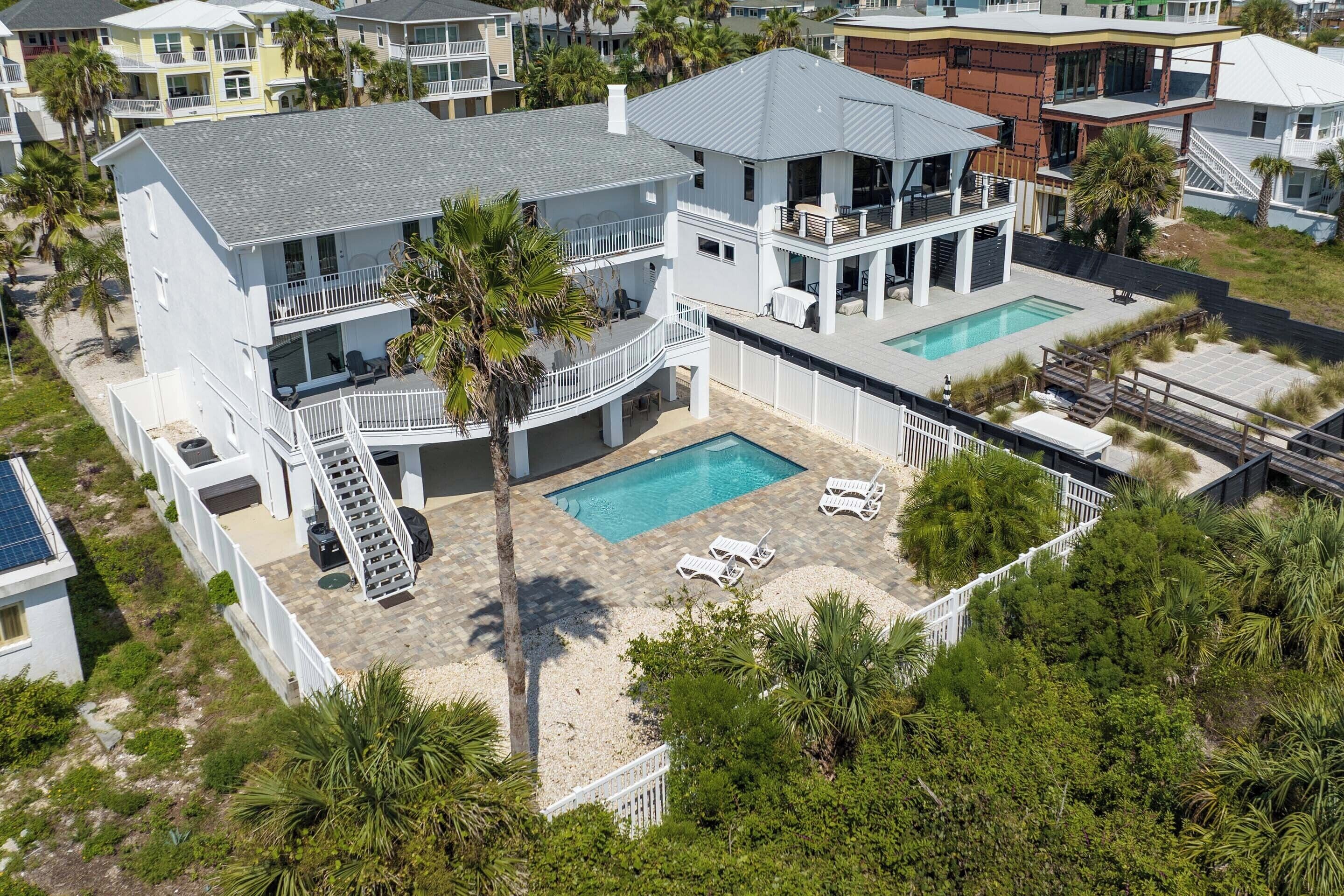 A two-story house with a swimming pool, a covered patio, and a fenced backyard.