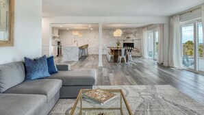 Ein modernes Wohnzimmer mit grauem Sofa, Couchtisch und Essbereich mit Tisch und Stühlen.