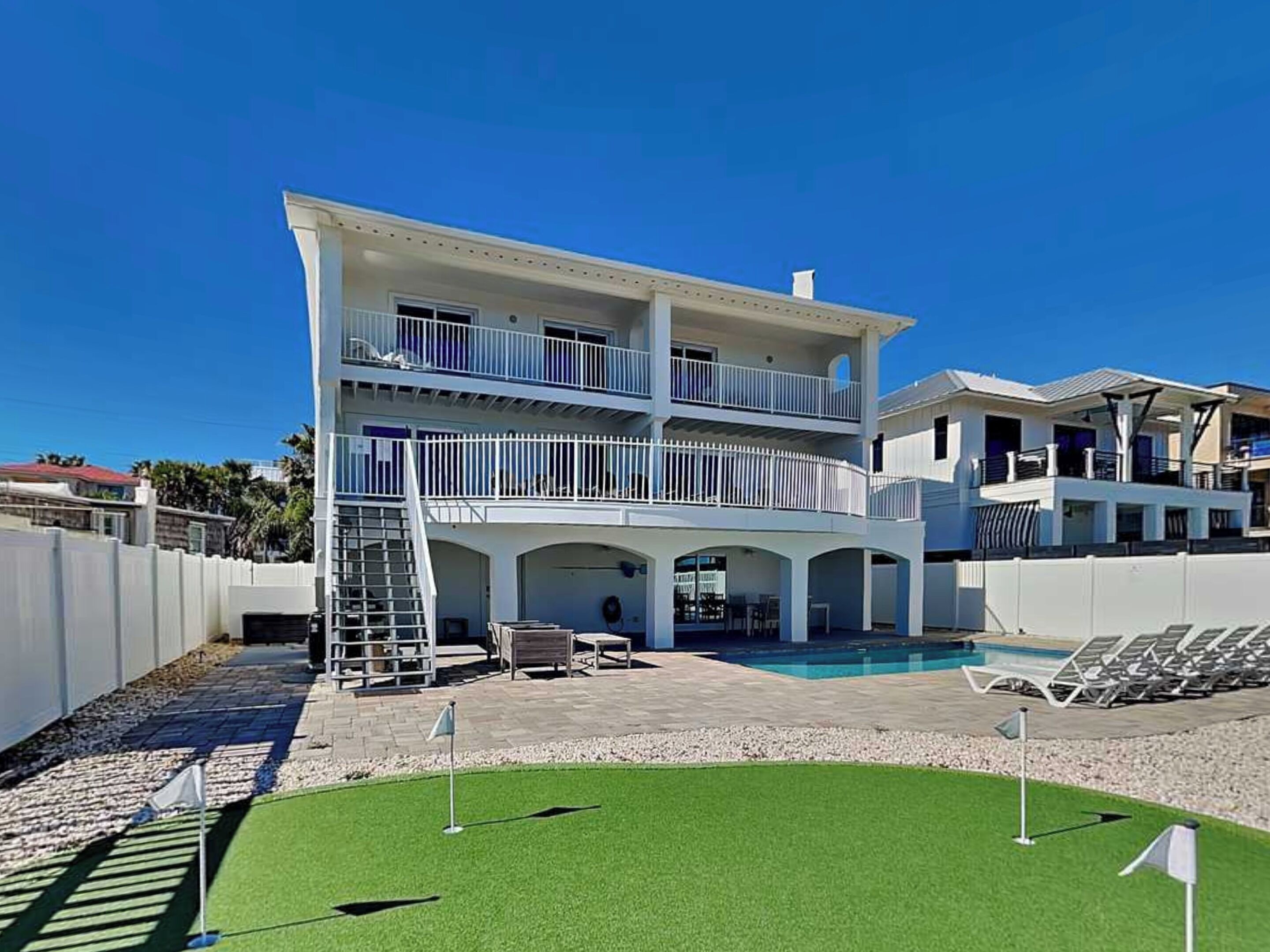 Un edificio de dos pisos con piscina, mobiliario exterior y un patio cubierto.