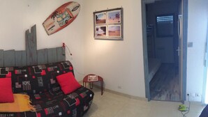 Een kamer met een bank, een tafeltje, een kast en een deur naar een andere kamer.