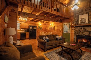 A cozy log cabin interior with a dining area, kitchen, and fireplace.