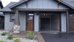 A residential building with a stone pillar, a wooden door, and a garage entrance.