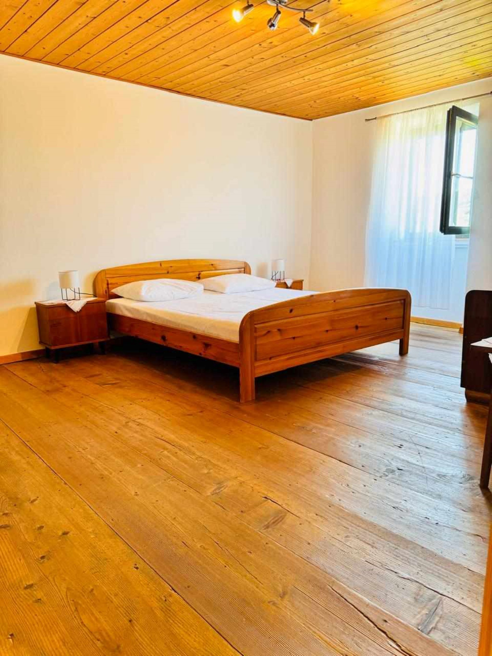 A wooden bed in a room with a wooden floor and ceiling.