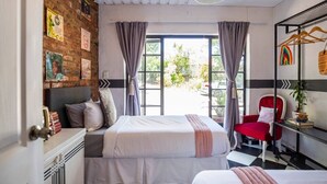 Um quarto com uma cama, uma cadeira vermelha, uma mesinha com uma planta e uma janela com cortinas.