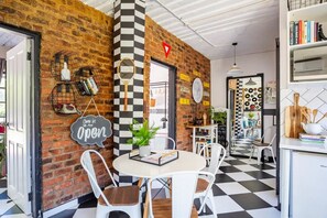 A cafe with a brick wall, checkered floor, and white furniture. - Retro-vintage New Yorker Apartment in Centurion (Centurion)