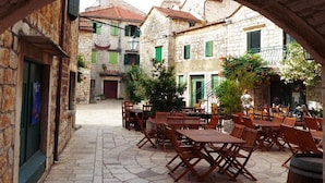 An outdoor café area with stone flooring and wooden tables and chairs. - Superior Apartment in Stari Grad (Stari Grad)