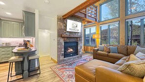 A modern interior with a stone fireplace, a leather sofa, and a large window overlooking a landscape.