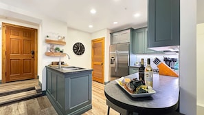 A modern kitchen with a central island, built-in appliances, and a dining area with a tray of food.