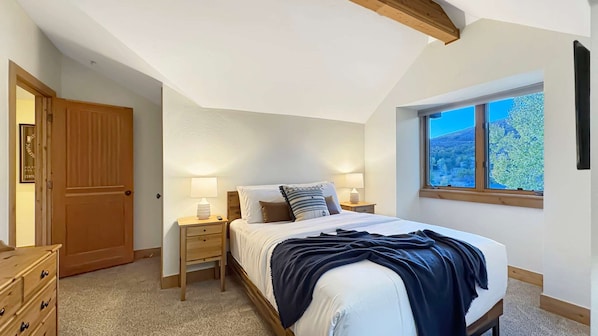 Un dormitorio con cama, mesitas de noche, armario y ventana con vistas.
