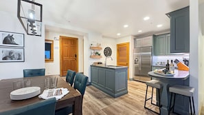 Una cocina moderna con una isla integrada, un comedor con mesa y sillas de madera y un refrigerador.