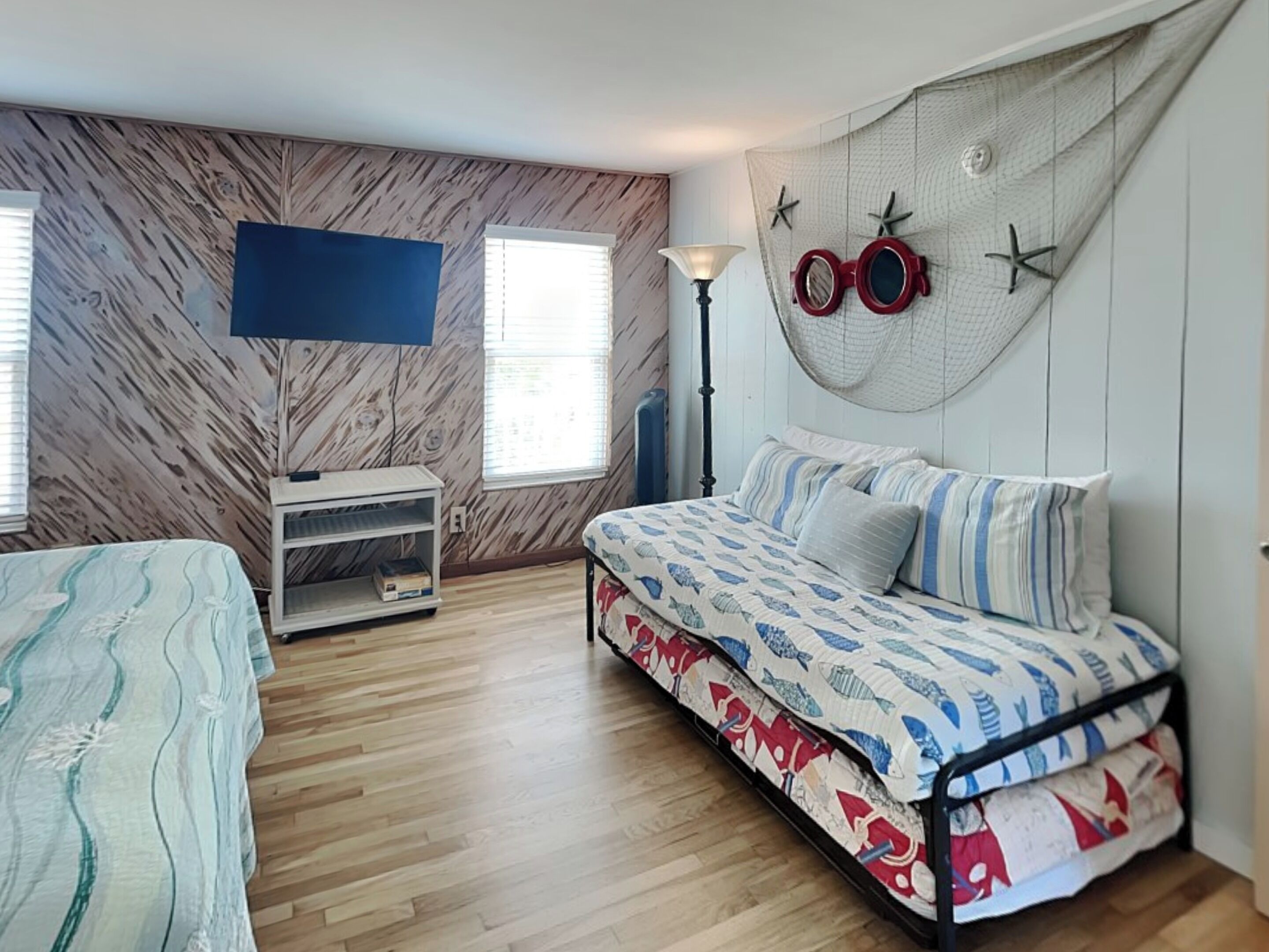 Een slaapkamer met een bed, een televisie, een lamp en een raam.