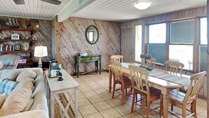 Un coin repas avec une table et des chaises en bois, un canapé, une petite table d’appoint et un ventilateur de plafond.