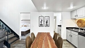 Un espacio habitable compacto con comedor, kitchenette y un dormitorio con cama y mesita de noche.
