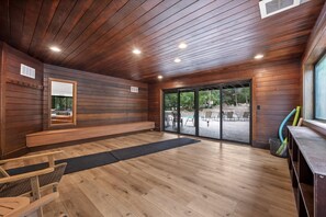 A modern interior with wooden paneling, a bench, a dining area, and a view of an outdoor patio.