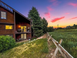 A two-story wooden cabin with a balcony, a dining area, and a view of the surrounding forest. - Peaceful Canyons Condo•Views•Pools•Hot Tubs•Perfect for Longer Summer Stays (Park City)