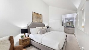 Une chambre à coucher moderne avec un lit, une table de chevet, une lampe et un tableau au mur.