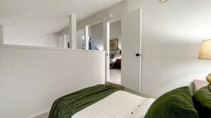 Une chambre à coucher avec un lit, une porte donnant sur une salle de bain et une petite table de chevet.