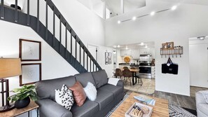 A modern living room with a grey sofa, a coffee table, and a staircase. - Canyons Village Retreat•Stunning Mtn Views•Community Pools, Hot Tubs, and More (Park City)