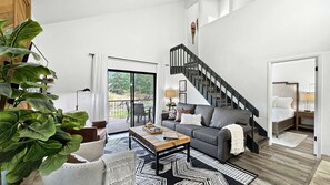 A spacious living room with a sofa, coffee table, and a staircase leading to a balcony.