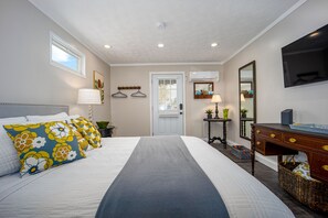 Un dormitorio con cama, mesitas de noche, cómoda, espejo y televisión.
