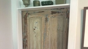 A rustic wooden door with peeling paint, a small round doorknob, and a shelf above holding a few decorative items. - Lovely, clean and walkable in the town of Luray.  (Luray)