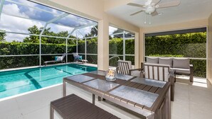 A poolside area with a glass-enclosed pool, outdoor furniture, and a ceiling fan. - THE WAVES HOUSE! 7 minute walk to the beach, 2 minute walk to the JW Marriott   (Marco Island)