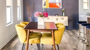 Un espace repas moderne avec un mur foncé, une table en bois et des chaises jaunes.