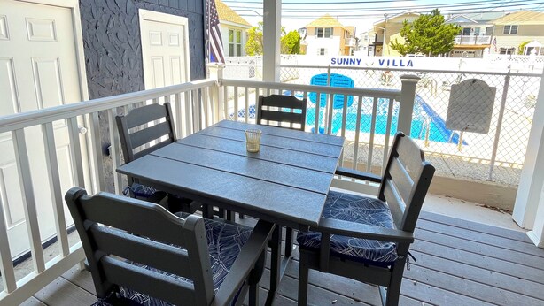 A covered outdoor area with a table and chairs, a pool in the background, and a sign reading "Sunny Villa". - AUGUST 8 TO 11 AVAILABLE ...  FAMILIES/COUPLES ONLY  
CUTE UNIT WITH POOL (Seaside Heights)